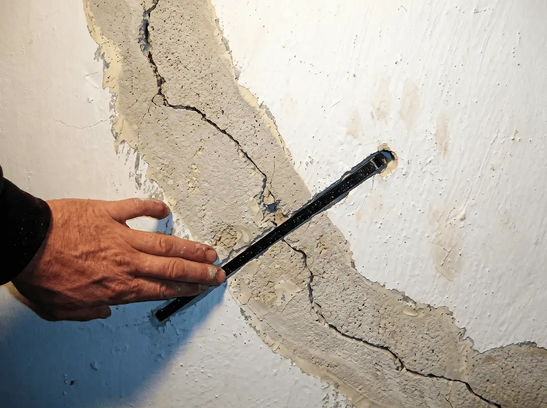 A wall with a large crack is being inspected by a professional in Louisville, KY