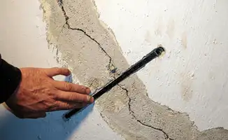 A wall with a large crack is being inspected by a professional in Louisville, KY